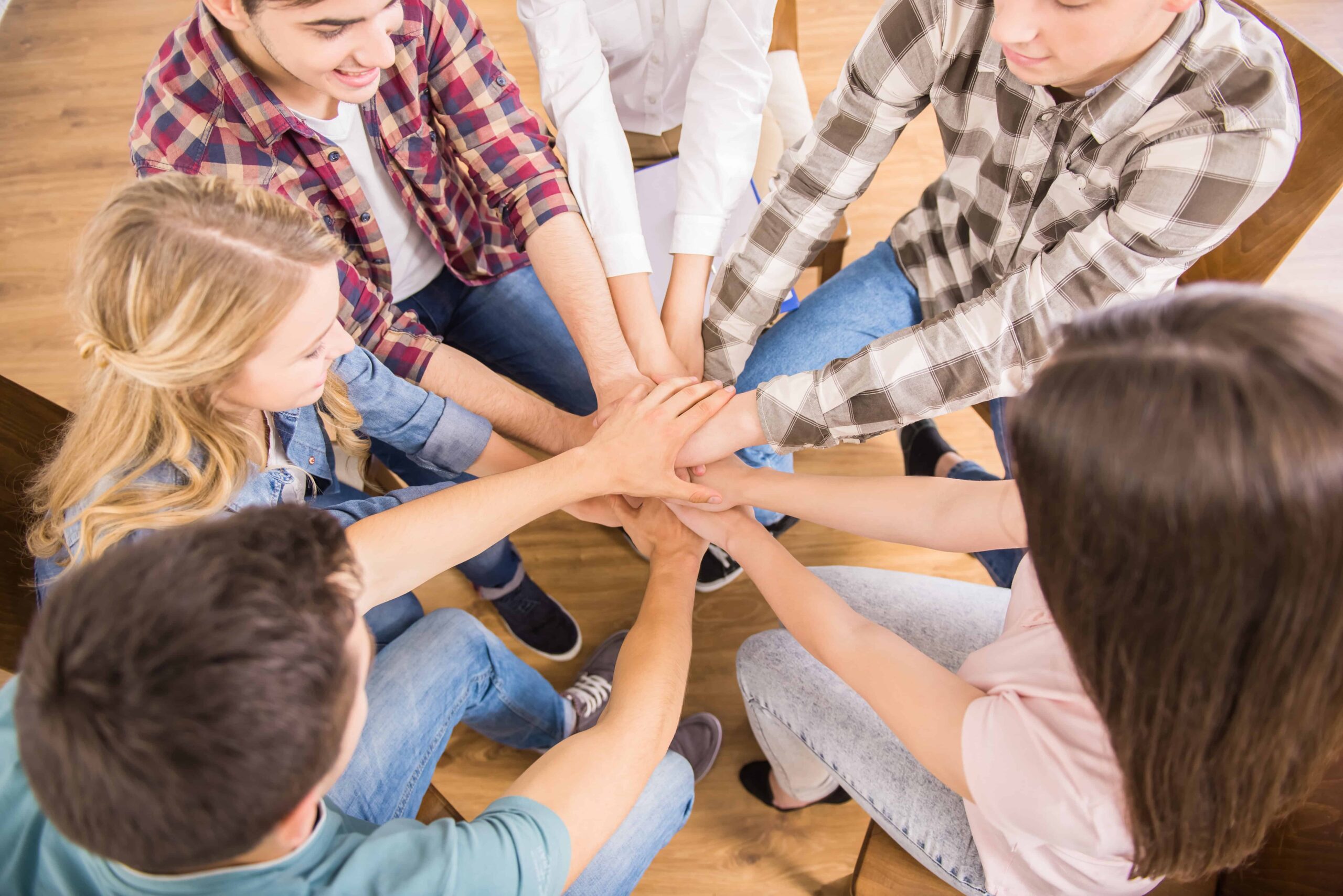 Group of people sitting in circle and supporting each other.